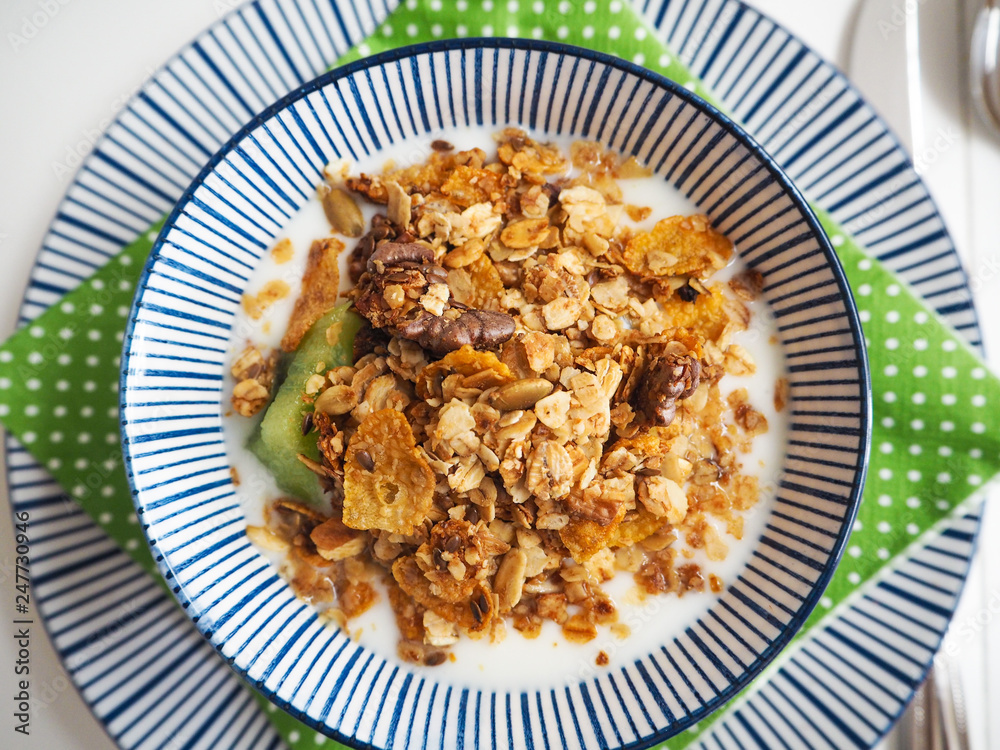 Flat lay of a blue and white striped bowl with homemade granola, kiwi and yoghurt Flat lay of a blue and white striped bowl with homemade granola, kiwi and yoghurt