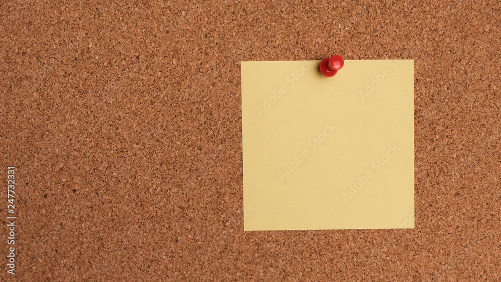 Sticky note on cork bulletin board Sticky note on cork bulletin board