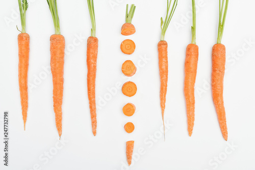 top view of composition with whole carrots with one sliced carrot in center isolated on white