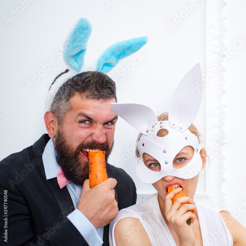 Surprised bunny couple wearing bunny ears and eat carrot. Sexy easter.