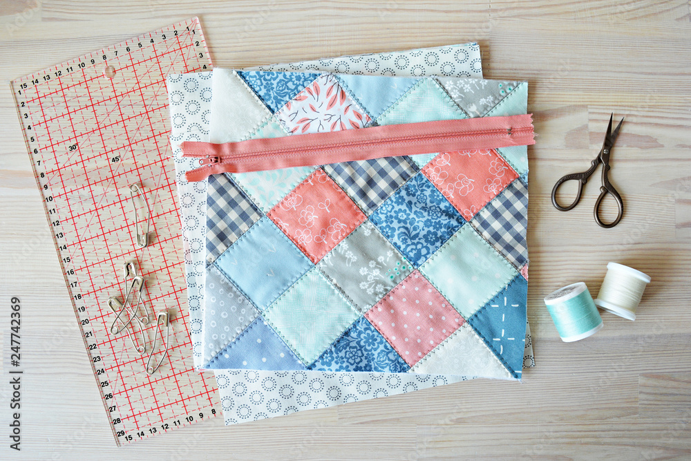 Obraz premium Working process: quilt, zipper, threads, retro scissors , quilting pins and ruler on the wooden table