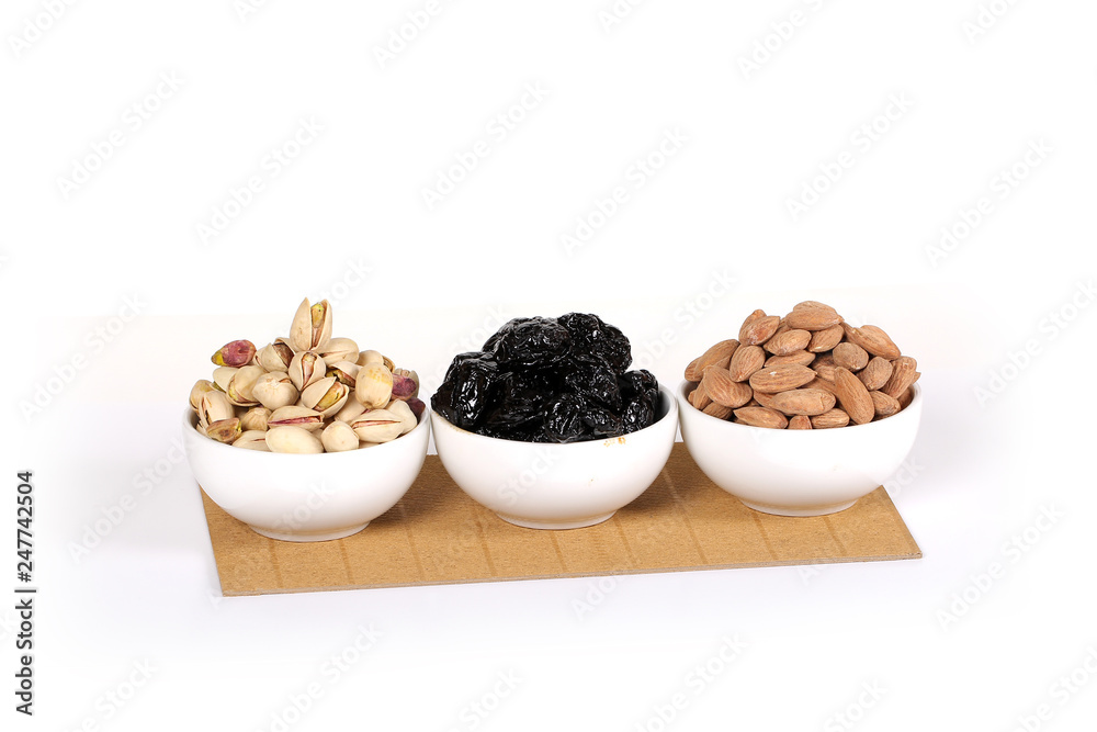 Assorted nuts on white, dry fruits, mix nuts, roasted almond, prunes, pistachio Assorted nuts on white, dry fruits, mix nuts, roasted almond, prunes, pistachio