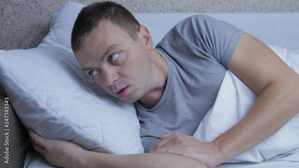 Young man having a nightmare and going back to sleep Young man having a nightmare and going back to sleep