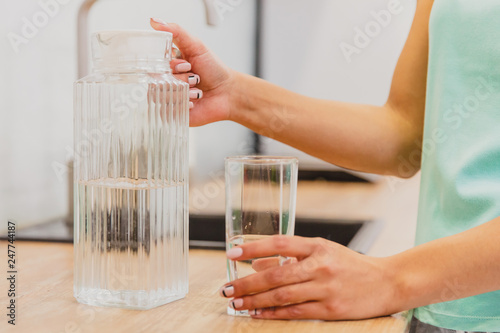 Happy beautiful young woman drinking water. Smiling caucasian female model holding transparent glass in her hand.