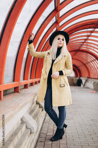 Street fashionable close up portrait of young hipster girl in yellow suit and black hat outdoors