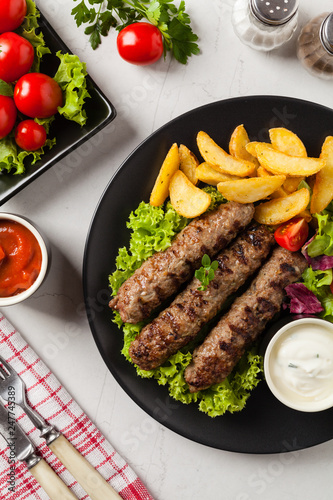 Traditional cevapcici served with baked potatoes. Flat lay. Stone background.