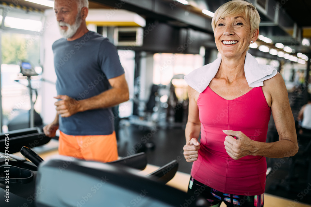 Senior people running on a treadmill in health club. Senior people running on a treadmill in health club.