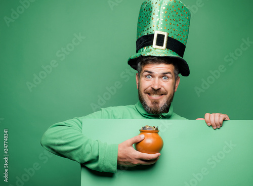 Green patricks background. Man in Patrick's suit smiling. Man in Saint Patrick's Day leprechaun party hat having fun on green background. photo