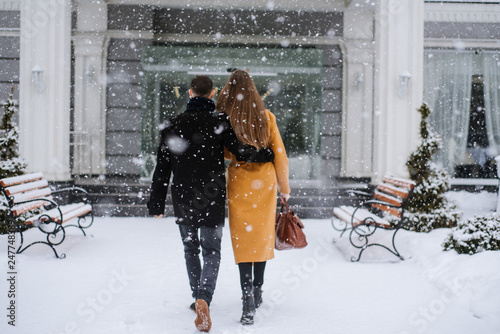 A couple enter the hotel in winter snowy day. Blurred image for background