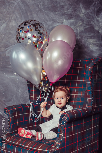 Close up portrait of cute adorable cheerful infant baby girl in dress playing with baloons, celebrating happy birthday. Baloons background, party concept. Childhoood, cute kid, happiness concept photo