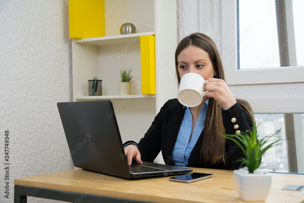 Successful young woman working on laptop and drinking coffee Successful young woman working on laptop and drinking coffee