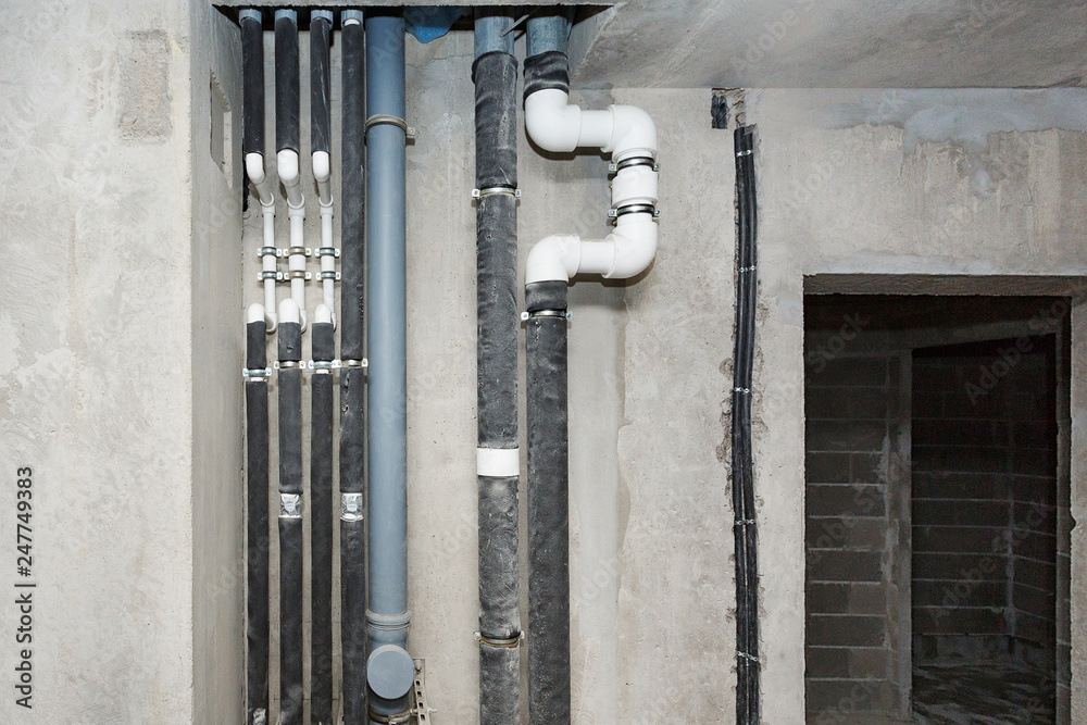 Pipes of heating and water supply system on the background of a concrete wall.
