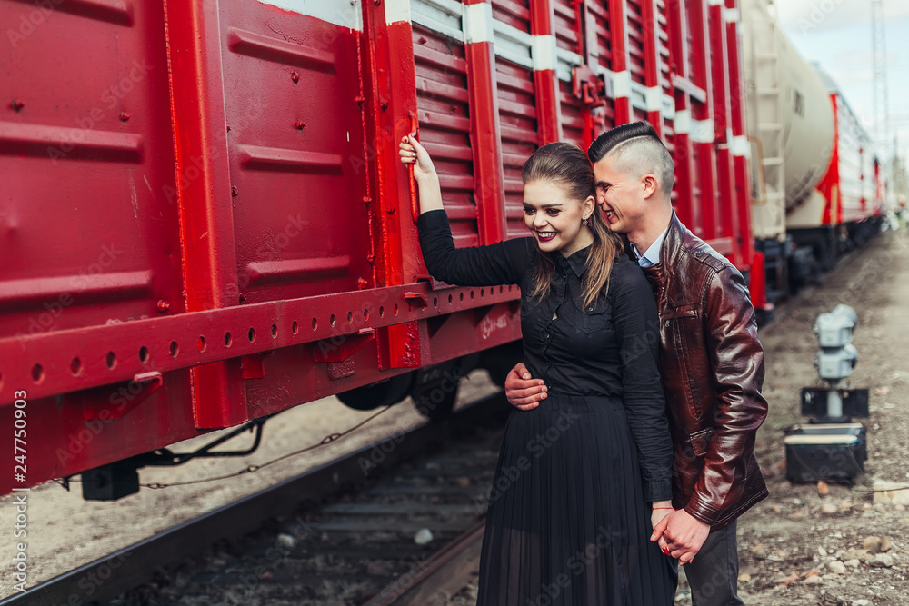 Romantic love in railway station  near red railway carriage in summer. Young gorgeous sexy hipster couple outdoors