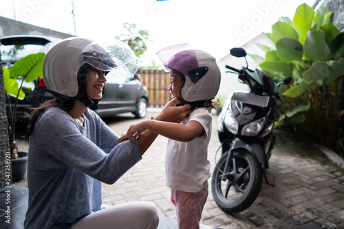 asian mom helped her daughter to put on helmet before going by motorcycle