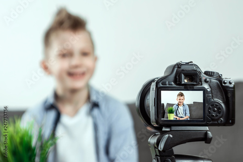The boy is sitting in front of a SLR camera, close-up. Blogger, blogging, technology, earnings on the Internet. copy space.
