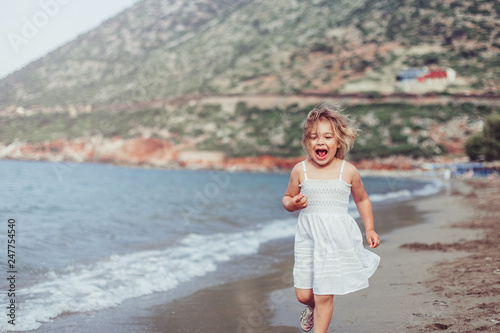 Cheerful happy emotional caucasain pretty girl on the beach coast of the ocean with rocks landscape having fun