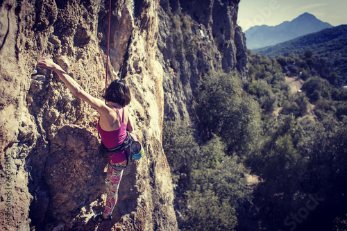 Woman climbing in Greece and beautiful forest and cliff landscape on the background