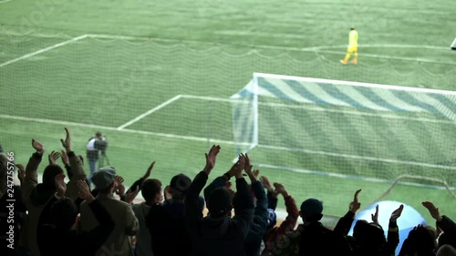 Silhouettes of fans in the background of a football field.