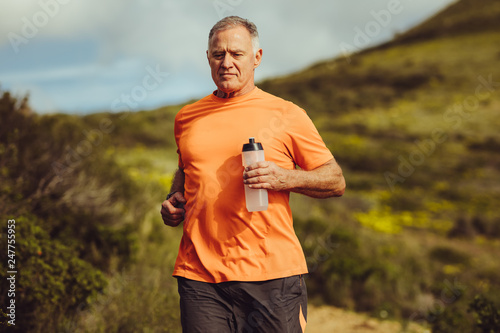 Senior man in fitness clothes running outdoors