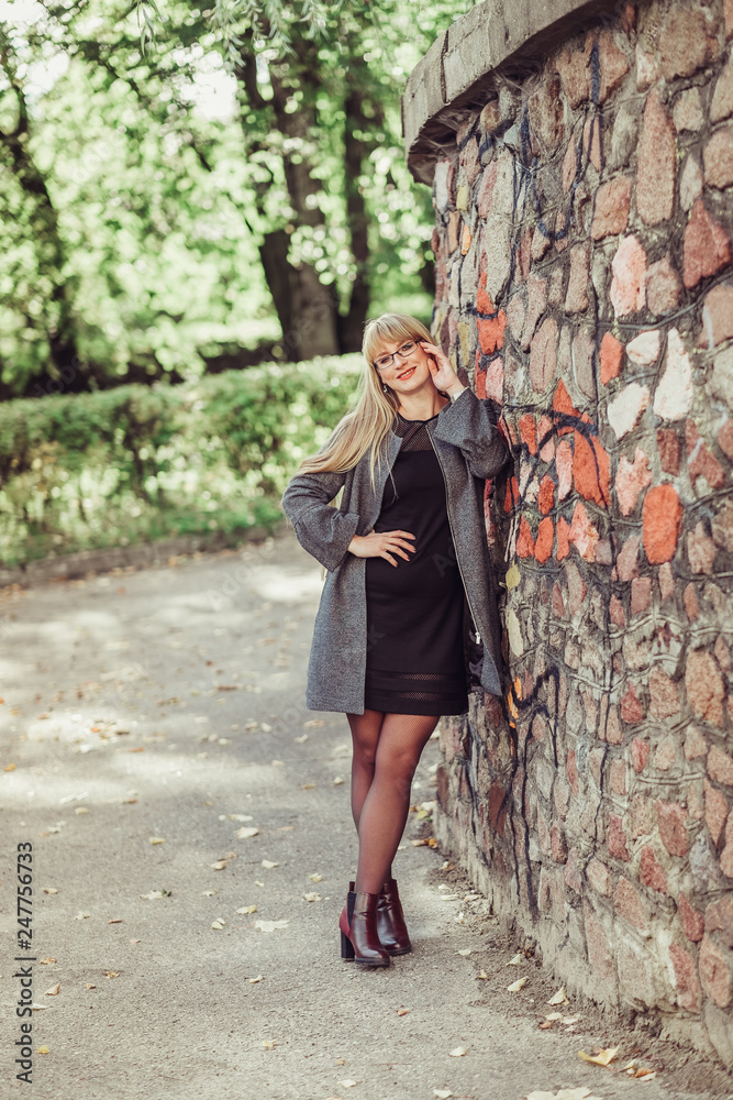 Happy cheerful portrait of young caucasian blondie woman with long hair walking outdoors in park