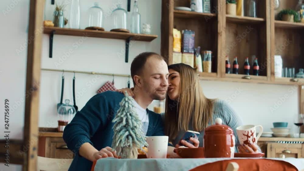 Pregnant wife and husband have breakfast in the kitchen with a smartphone Pregnant wife and husband have breakfast in the kitchen with a smartphone