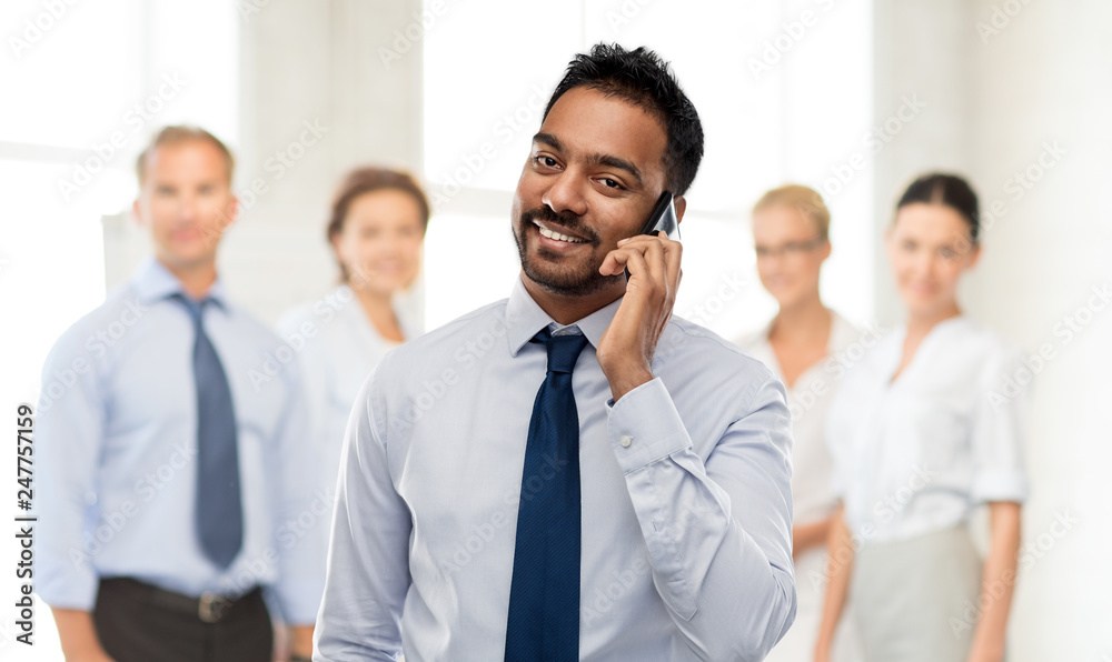 business, communication and people concept - smiling indian businessman calling on smartphone over colleagues on office background business, communication and people concept - smiling indian businessman calling on smartphone over colleagues on office background