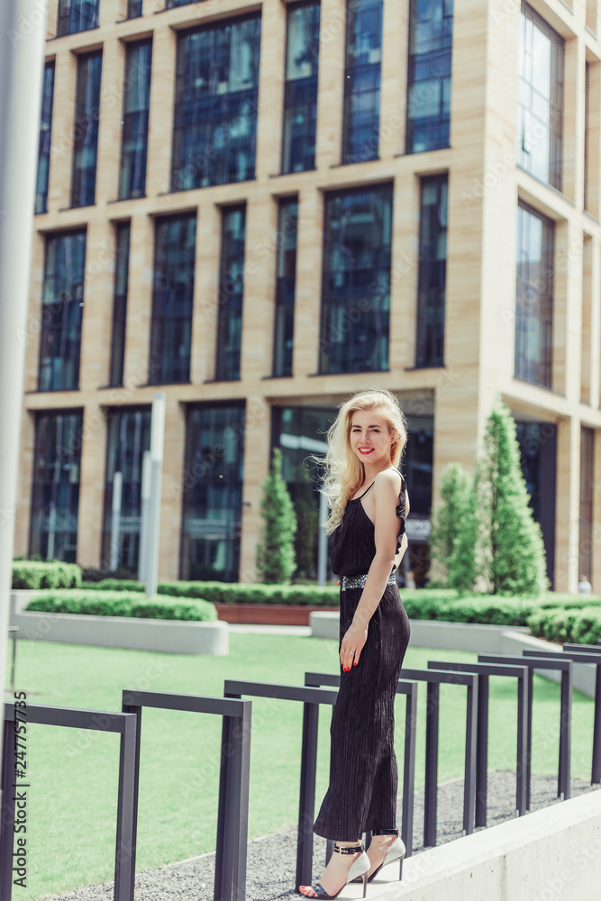 Sexy young rich blondie caucasian woman walking near skyscrapers, luxury buisness center