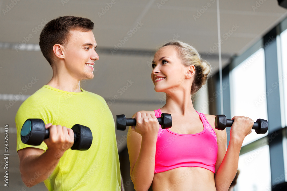 sport, fitness and people concept - couple with dumbbells exercising in gym