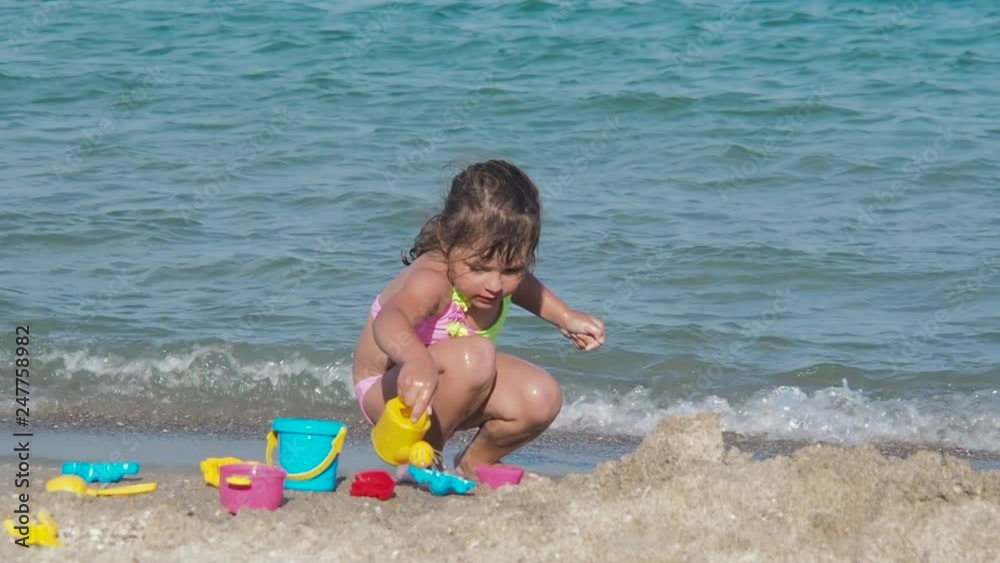 Kid playing with sand on beach. Cute little girl plays with toys on the sand near the seashore. Kid playing with sand on beach. Cute little girl plays with toys on the sand near the seashore.