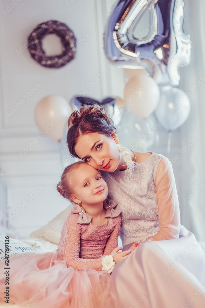 Fototapeta premium Close up portrait of elegant stylish mother and daughter in fashion dresses playing together, celebrating happy birthday. Baloons background, party concept. Childhoood, cute kid, carefull mother
