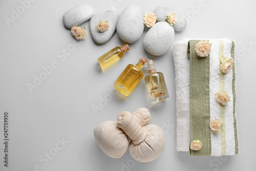 Spa composition with herbal bags, towel and stones on light background