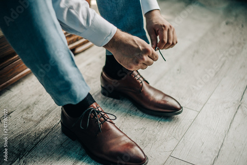 young guy tying shoelace on leather shoes photo