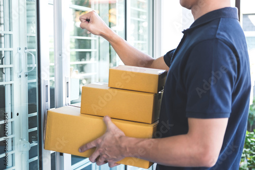 Wallpaper Mural Delivery man standing with parcels in hands outdoors waiting homeowner open door, Home delivery service and working with service mind Torontodigital.ca