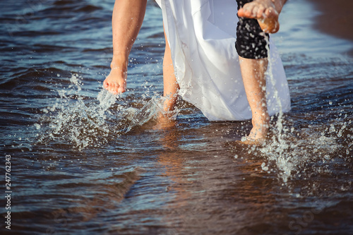 Legs of man and woman walking on the beach ot sea