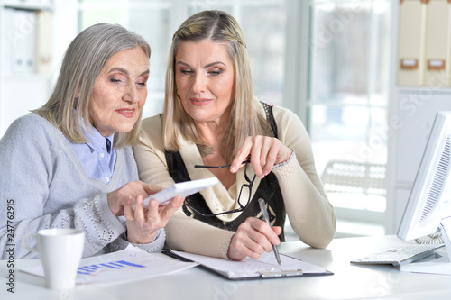 two excited mature women working in office