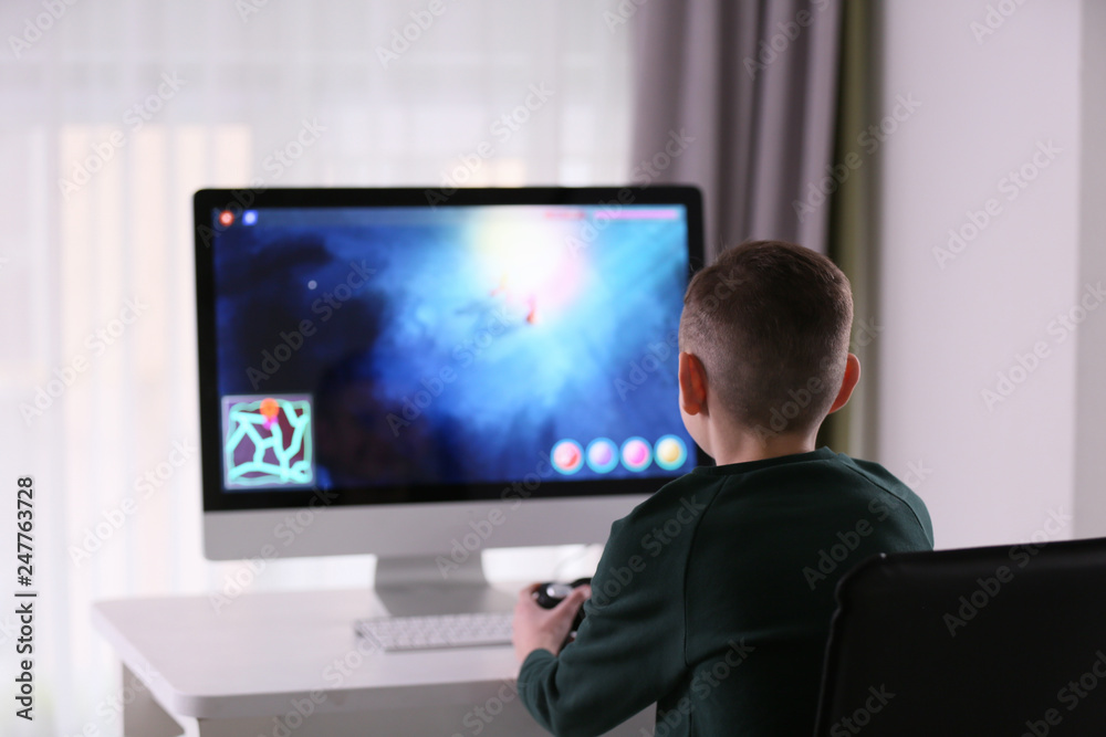 Cute little boy playing computer game at home Cute little boy playing computer game at home