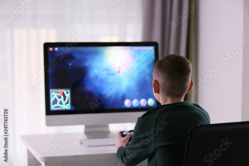 Cute little boy playing computer game at home