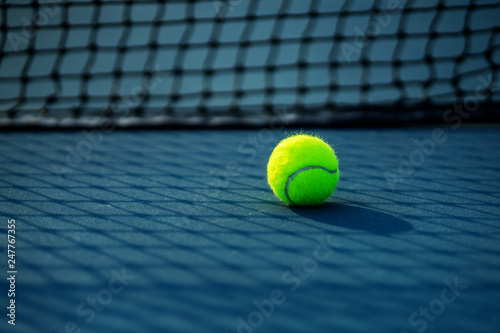 Tennis Ball on the Court with the Net in the background © somchaip