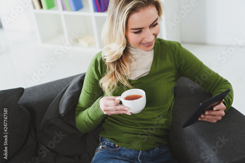 attractive woman holding cup with tea while studying with e-book at home photo