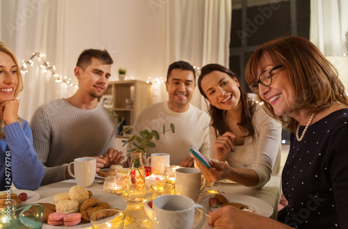 celebration, holidays and people concept - happy family with smartphone having tea party at home