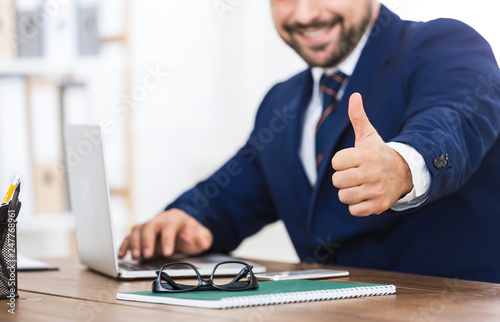 Obraz na plátně Successful businessman showing thumb up at workplace