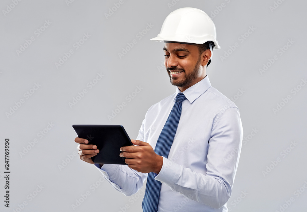 architecture, technology, construction business and building - smiling indian architect or businessman in helmet with tablet computer over grey background