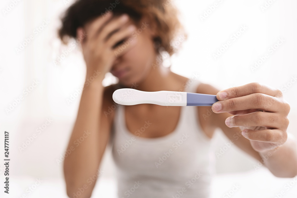 Upset black woman holding negative pregnancy test Upset black woman holding negative pregnancy test