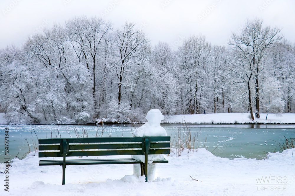 Schneemann sitzt auf Bank im Park mit See im Winter, Geduld Warten