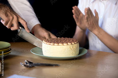 Close up of man cutting birthday cake in office