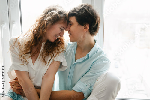 Free Download Happy girl and man kissing near window in home.  - GFXLoad