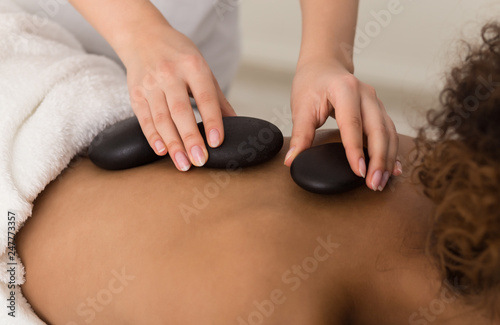 Masseur placing stone on back of woman