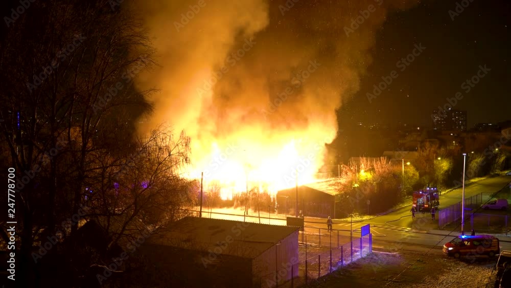 Firemens trying to control fire in an industrial building during the night.