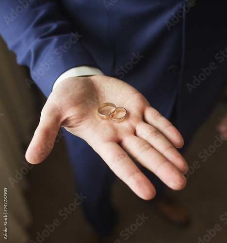 Close up top view of opened palm of man holding two golden wedding rings. Groom or groomsmen ready for wedding ceremony. Color photography.