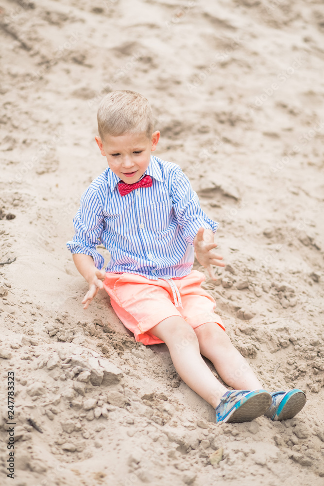 Portrait of cute happy white child showing his dirty sandy hands after playing with sand at river beach during summer weekend. Vertical color photography. Portrait of cute happy white child showing his dirty sandy hands after playing with sand at river beach during summer weekend. Vertical color photography.